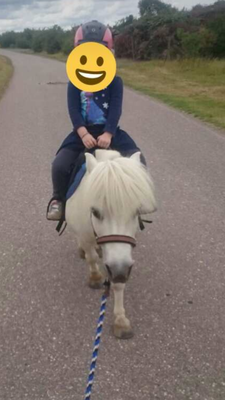 Kind reitet auf weißem Pony