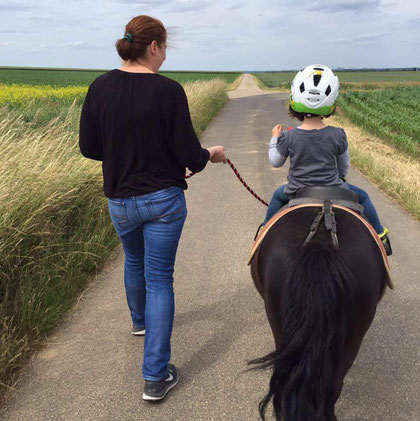 Mutter und Tochter spazieren mit Pony